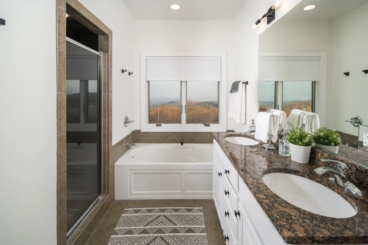 A spa-inspired bathroom featuring a modern bathtub beneath a window that frames a scenic view. The vanity with mirrors offers space for self-care routines, while soft towels and a gentle ambiance evoke a luxurious, rejuvenating spa experience.