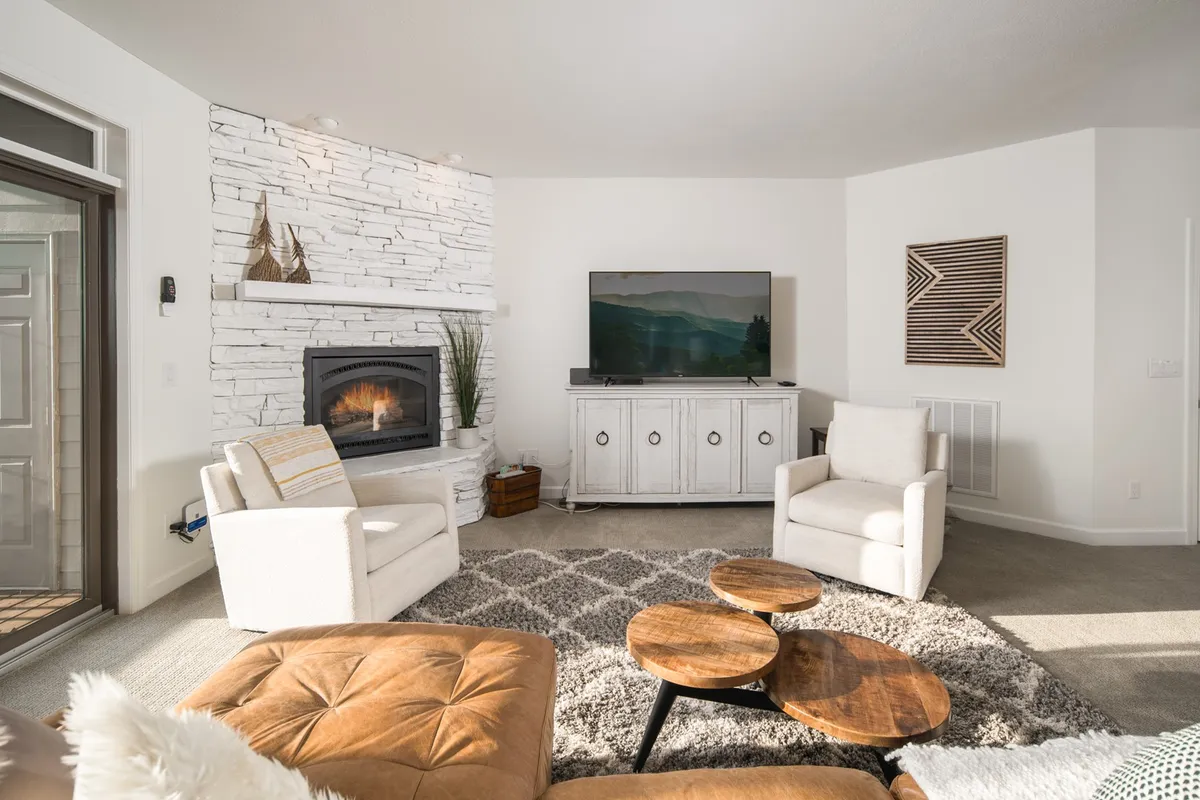 A comfortable living room featuring a glowing fireplace, television, coffee table, and plush armchairs. The space is arranged for relaxation and socializing, suggesting cozy evenings spent reminiscing about the day’s adventures or celebrating with loved ones during holiday seasons.