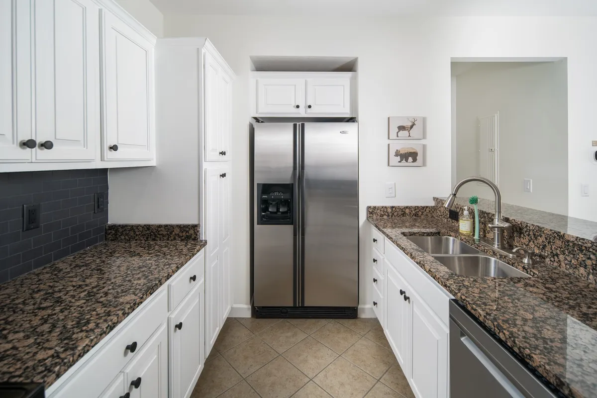 A modern kitchen with stainless steel appliances, granite countertops, and crisp white cabinetry. The space is elegant and welcoming, with plenty of room for preparing meals or sharing an intimate dinner.